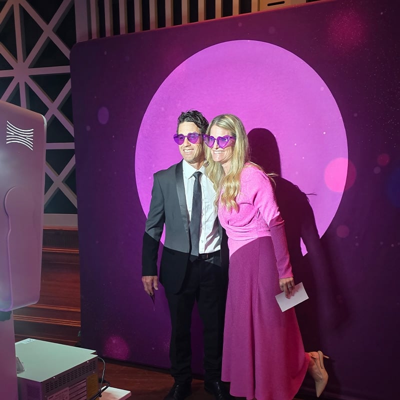 Spotlight photo booth Couple standing in front of backdrop with spotlight on them ready for a photo.